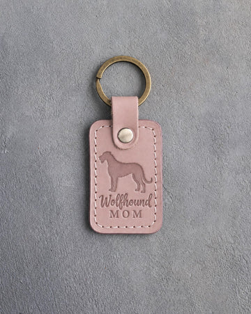 Blush pink leather keychain debossed with an Irish Wolfhound silhouette and the words Wolfhound MOM, on gray concrete