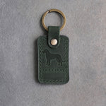 Forest green leather keychain debossed with an Irish Wolfhound silhouette above THE GIANT, on gray concrete