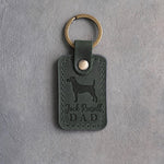 Forest green leather keychain debossed with a Jack Russell terrier and Jack Russell DAD, on gray concrete