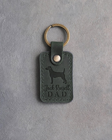 Forest green leather keychain debossed with a Jack Russell terrier and Jack Russell DAD, on gray concrete