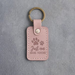 Blush pink leather keychain debossed with a pair of paw prints and the words Just one MORE FOSTER, on gray concrete