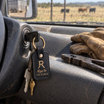 Black Keys to THE RANCH keychain with a gold brand hanging from the ignition key of a ranch pickup, work gloves and fence pliers on the dash