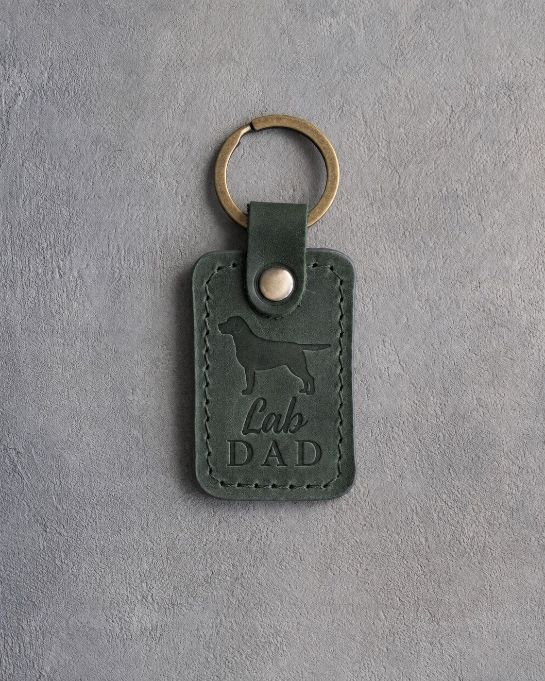 Forest green leather keychain debossed with a Labrador Retriever silhouette and the words Lab DAD, on gray concrete