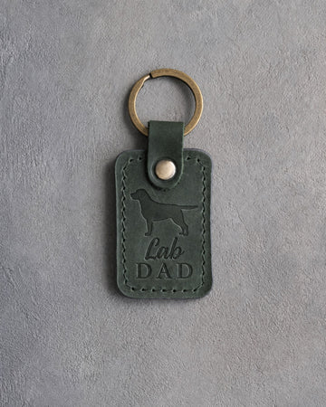 Forest green leather keychain debossed with a Labrador Retriever silhouette and the words Lab DAD, on gray concrete
