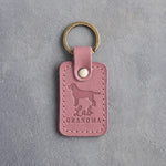 Parisian Blossom pink leather keychain debossed with a Labrador silhouette and the words Lab GRANDMA, on gray concrete
