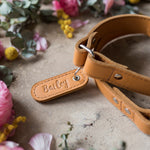Close-up of a leather dog leash name tab with the name Bailey debossed in cursive