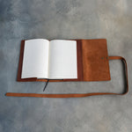 Open leather wrap journal with a lined refillable insert and its long strap