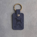 Blueberry navy leather keychain debossed with a Beagle silhouette and the words Led by THE NOSE, on gray concrete