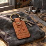 Lefty Loosey Righty Tighty keychain in caramel leather on car keys resting on a garage workbench beside a socket set