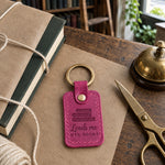 Bright pink Lends me HER BOOKS keychain on kraft paper beside a book half wrapped with cotton string