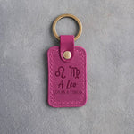 Fuchsia pink leather keychain debossed with Leo and Virgo zodiac glyphs above A Leo and LOVES A VIRGO, on gray concrete