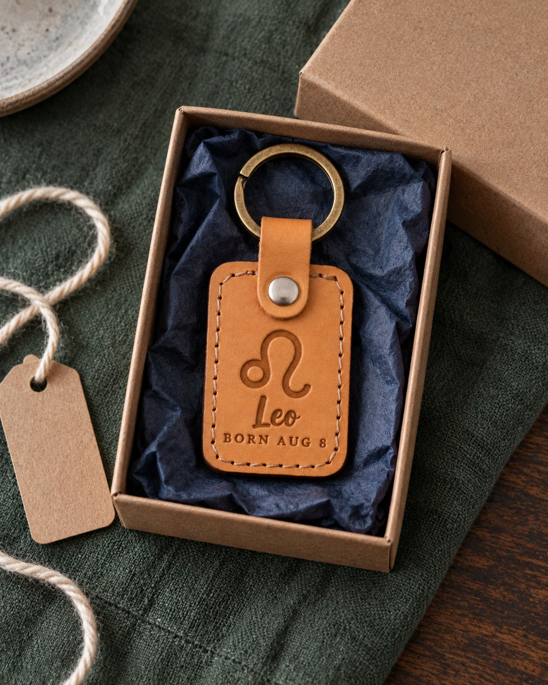 Golden tan Leo keychain on car keys resting on a summer beach towel in bright afternoon sun