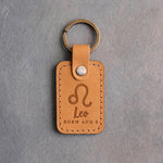 Indian Summer golden tan leather keychain debossed with the Leo zodiac glyph above Leo and BORN AUG 8, on gray concrete