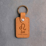 Indian Summer golden tan leather keychain debossed with the Leo zodiac glyph above Leo and FIRE SIGN, on gray concrete