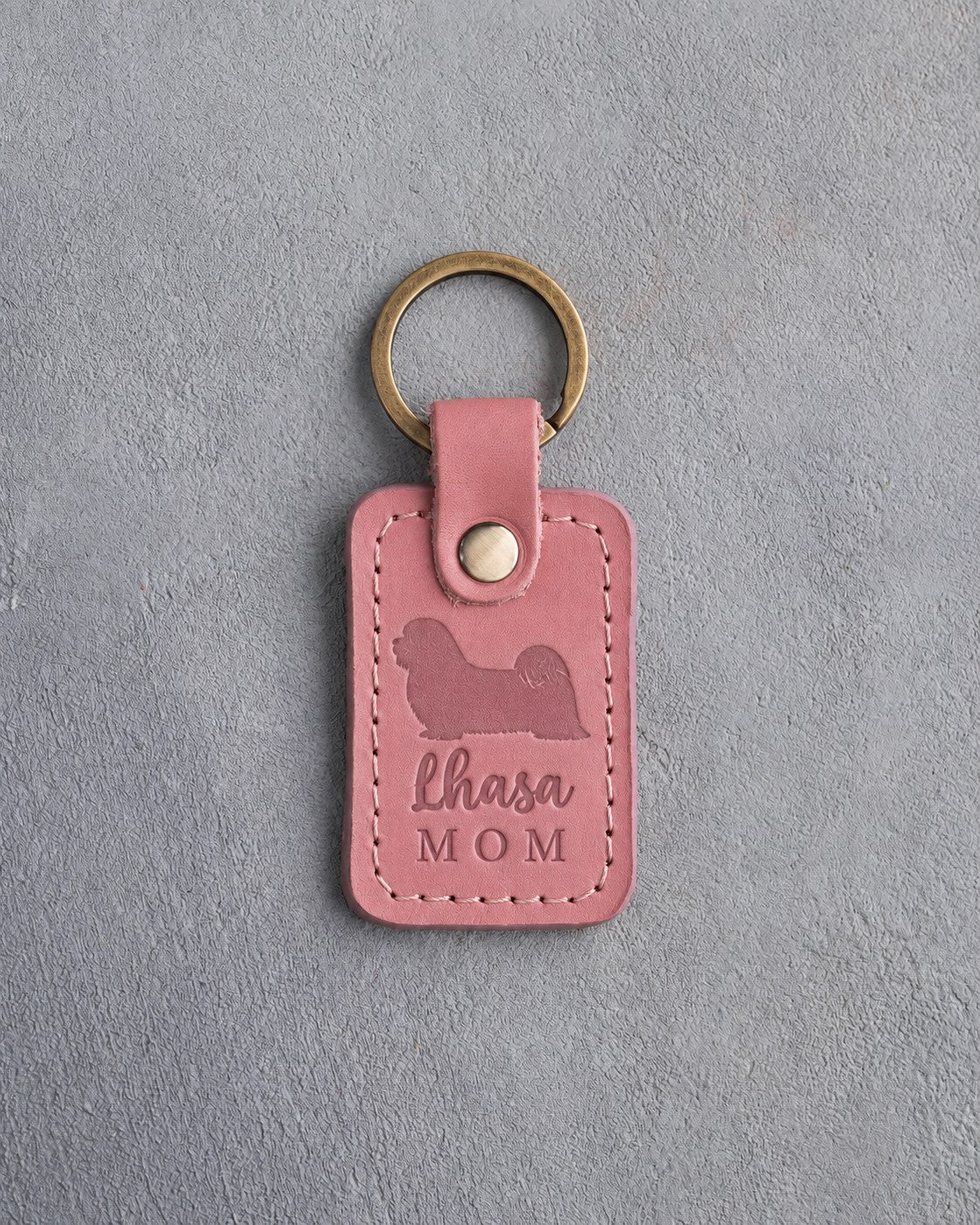 Parisian Blossom pink leather keychain debossed with a Lhasa Apso silhouette and the words Lhasa MOM, on gray concrete