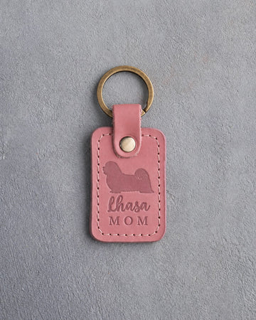 Parisian Blossom pink leather keychain debossed with a Lhasa Apso silhouette and the words Lhasa MOM, on gray concrete