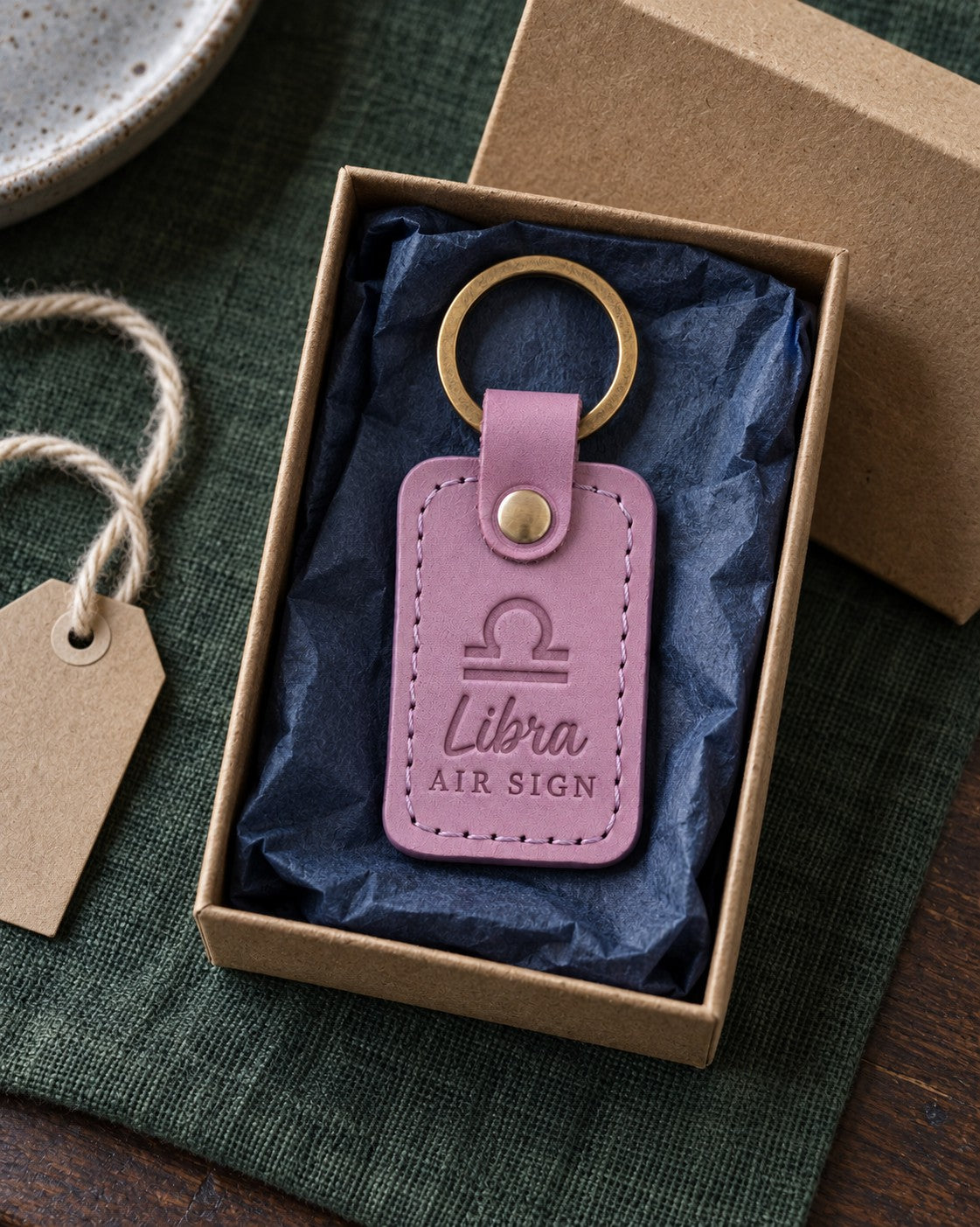 Lilac Libra keychain on a key ring beside an open book on a cafe table in soft autumn light