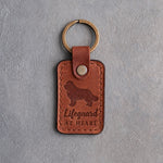 Arizona tan leather keychain debossed with a Newfoundland and the words Lifeguard AT HEART, on gray concrete