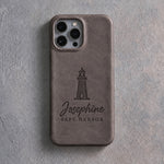 Back of a country gray leather iPhone case debossed with a lighthouse above Josephine and SAFE HARBOR below the camera, on gray plaster