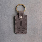 Country Gray leather keychain debossed with a lighthouse above Josephine and SAFE HARBOR, on gray plaster