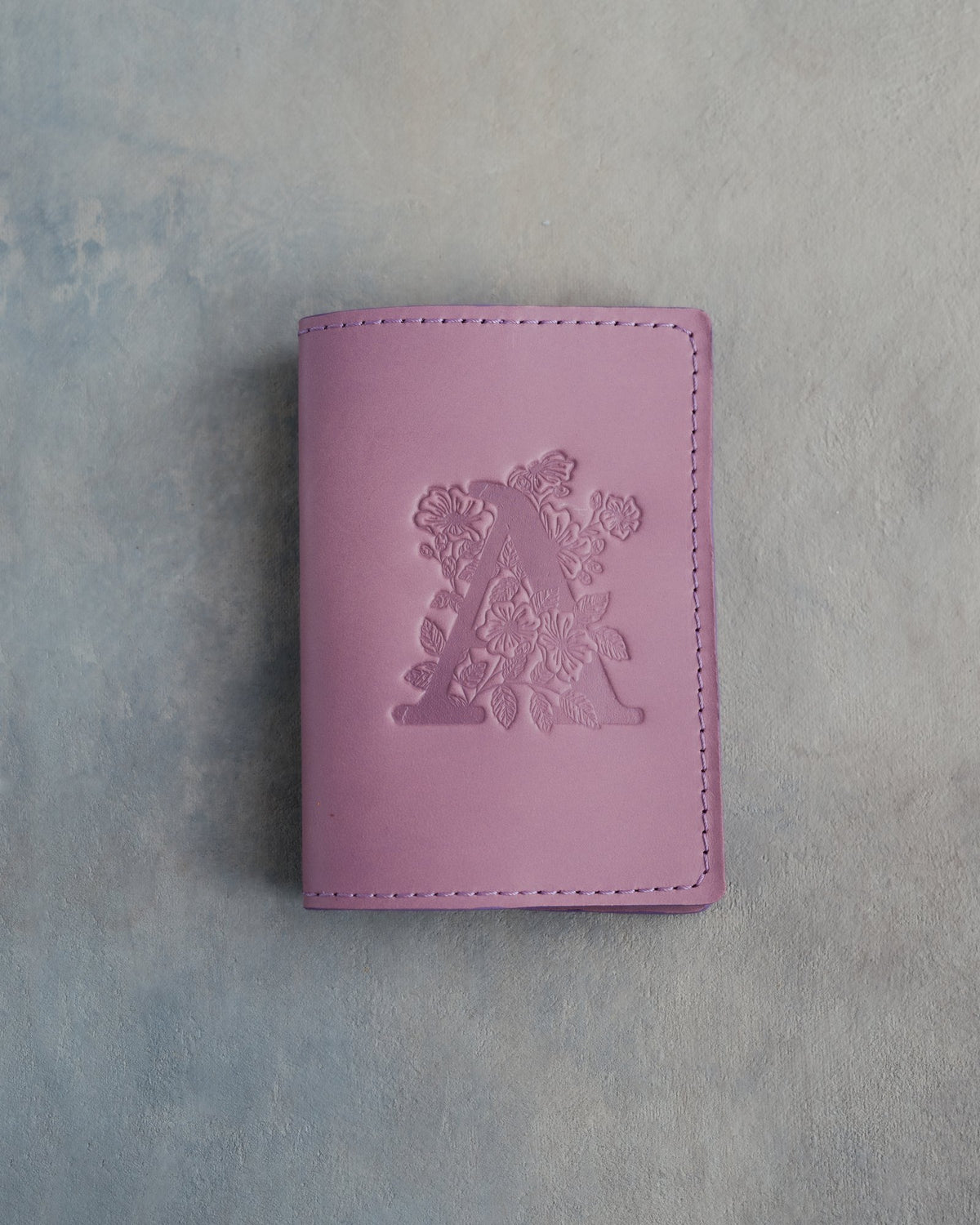 Lilac leather passport cover with a large floral initial A pressed into the front