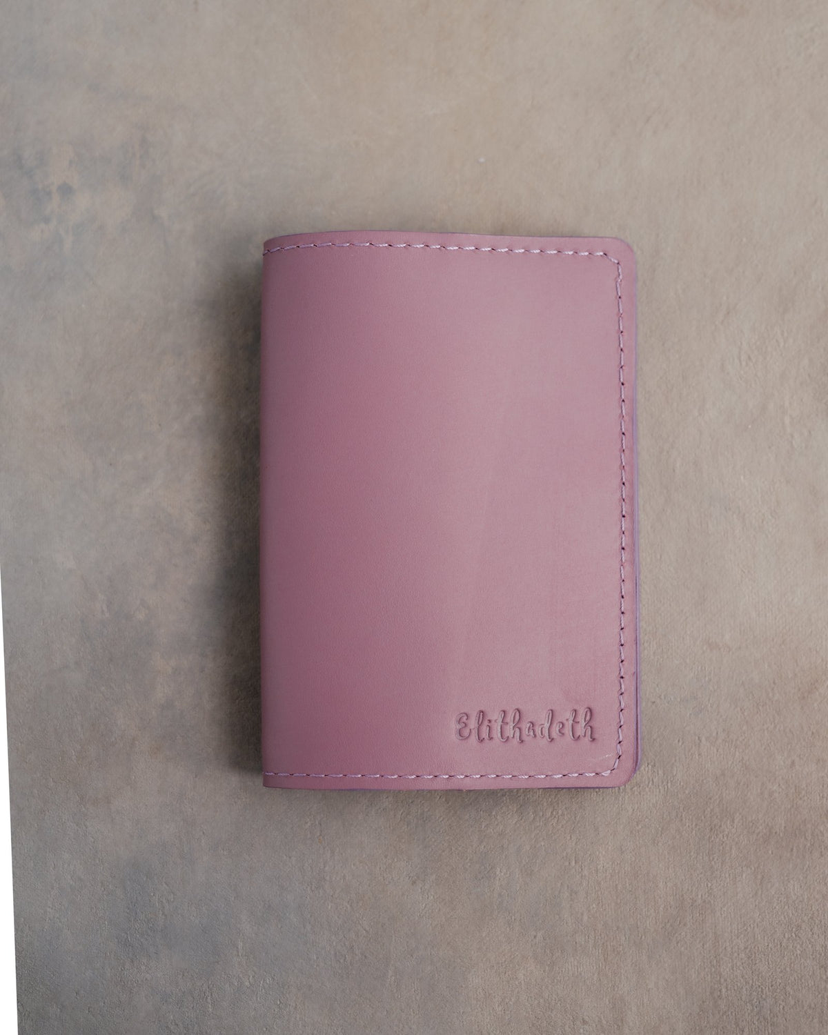 Lilac leather passport cover with a name in small script pressed into the bottom corner