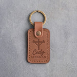 Caramel leather keychain debossed with a utility pole and crossarm above the name Cody and LINEMAN, on gray plaster