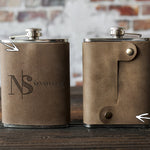 A real logo order: front and back of a leather hip flask with a company monogram pressed in and the snap strap on the back