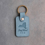 Turquoise leather keychain debossed with a New York State silhouette and a heart notch on Long Island above Long Island and 516, on gray concrete