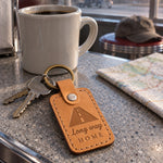 Tan Long way HOME keychain on car keys on the dashboard during a road trip
