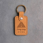 Golden tan leather keychain debossed with a road to the horizon above Long way and HOME