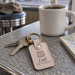 Pale gray Lost ON PURPOSE keychain on car keys resting on a sunlit dashboard