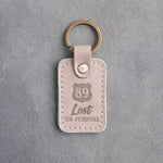 Gray sand leather keychain debossed with a route shield numbered 89 above Lost and ON PURPOSE