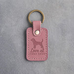 Parisian Blossom pink leather keychain debossed with a dachshund and the words Love at FIRST SNIFF, on gray concrete