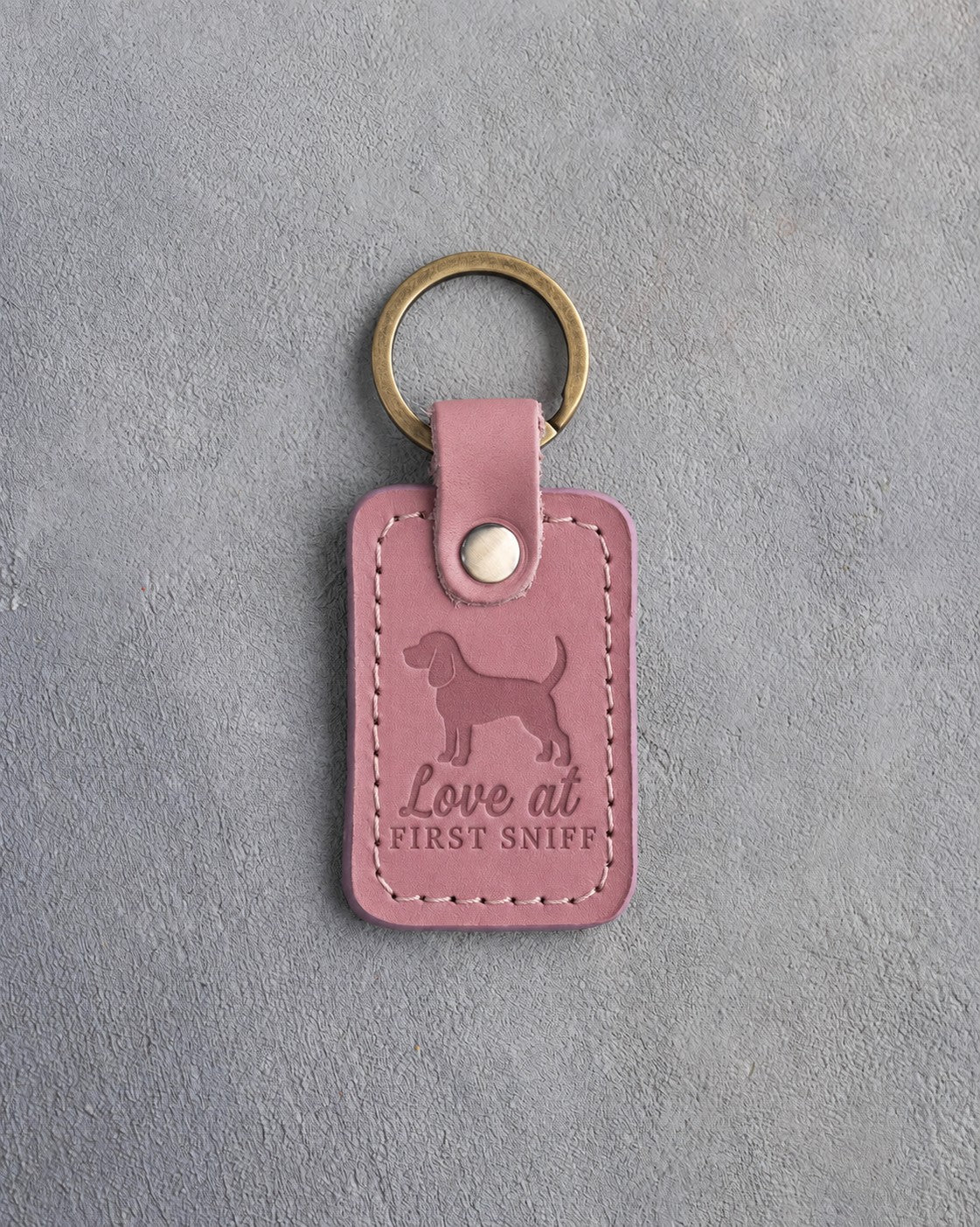 Parisian Blossom pink leather keychain debossed with a dachshund and the words Love at FIRST SNIFF, on gray concrete