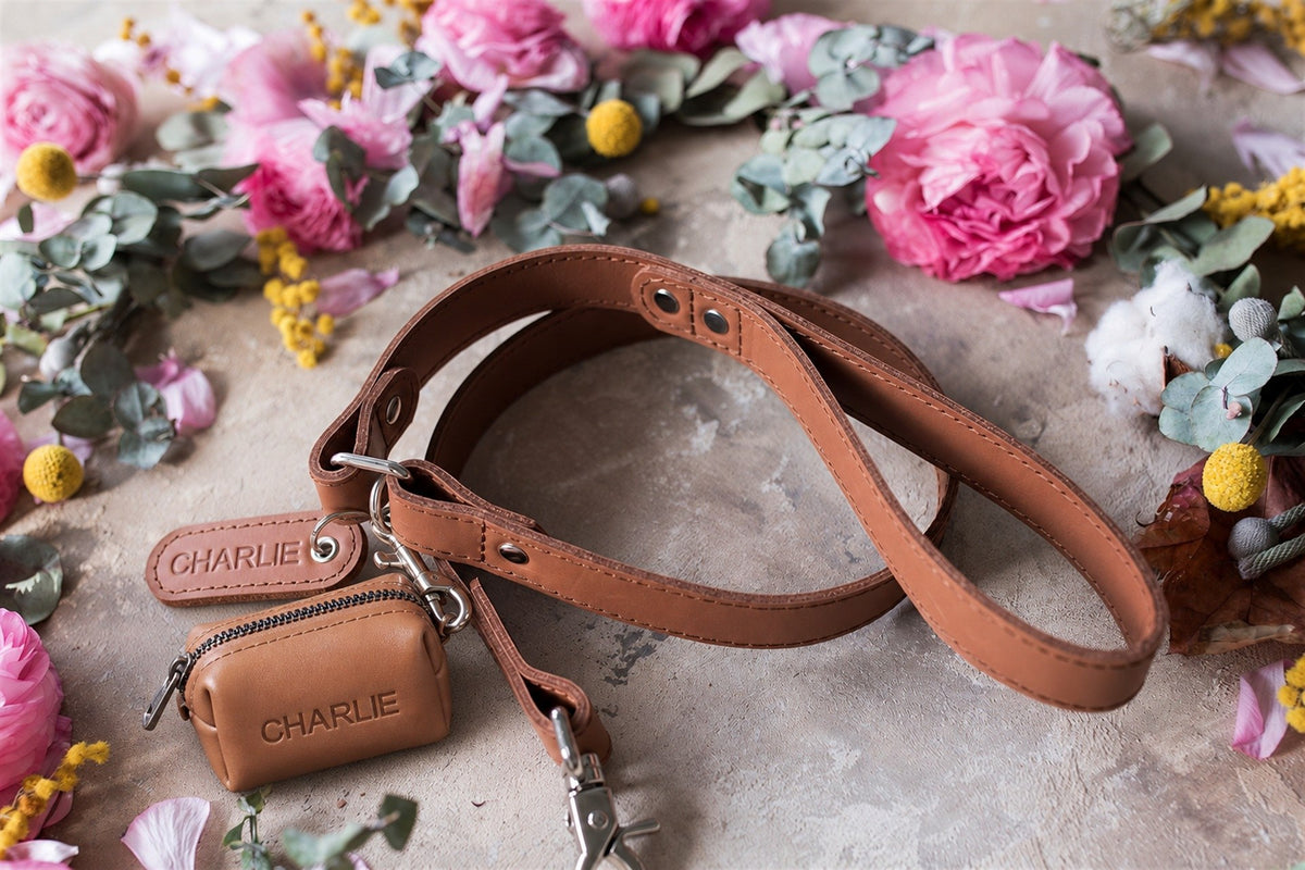 Caramel leather dog leash with a matching zip poop bag holder, both with the name Charlie