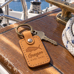 Indian summer Grayson MAHI MAHI keychain in full-grain leather on the worn teak cockpit table of a sailboat beside a coiled white dock line