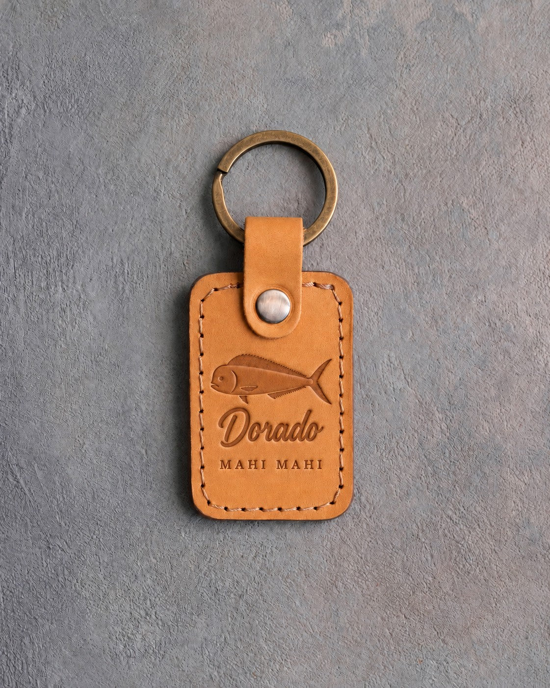 Indian summer leather keychain debossed with a mahi mahi above Dorado and MAHI MAHI, on gray concrete