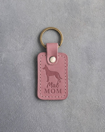 Parisian Blossom pink leather keychain with a debossed Malinois and the words Mal MOM, on gray concrete