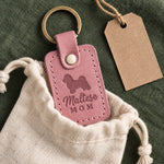 Parisian Blossom pink Maltese Mom leather keychain placed in a warm everyday setting