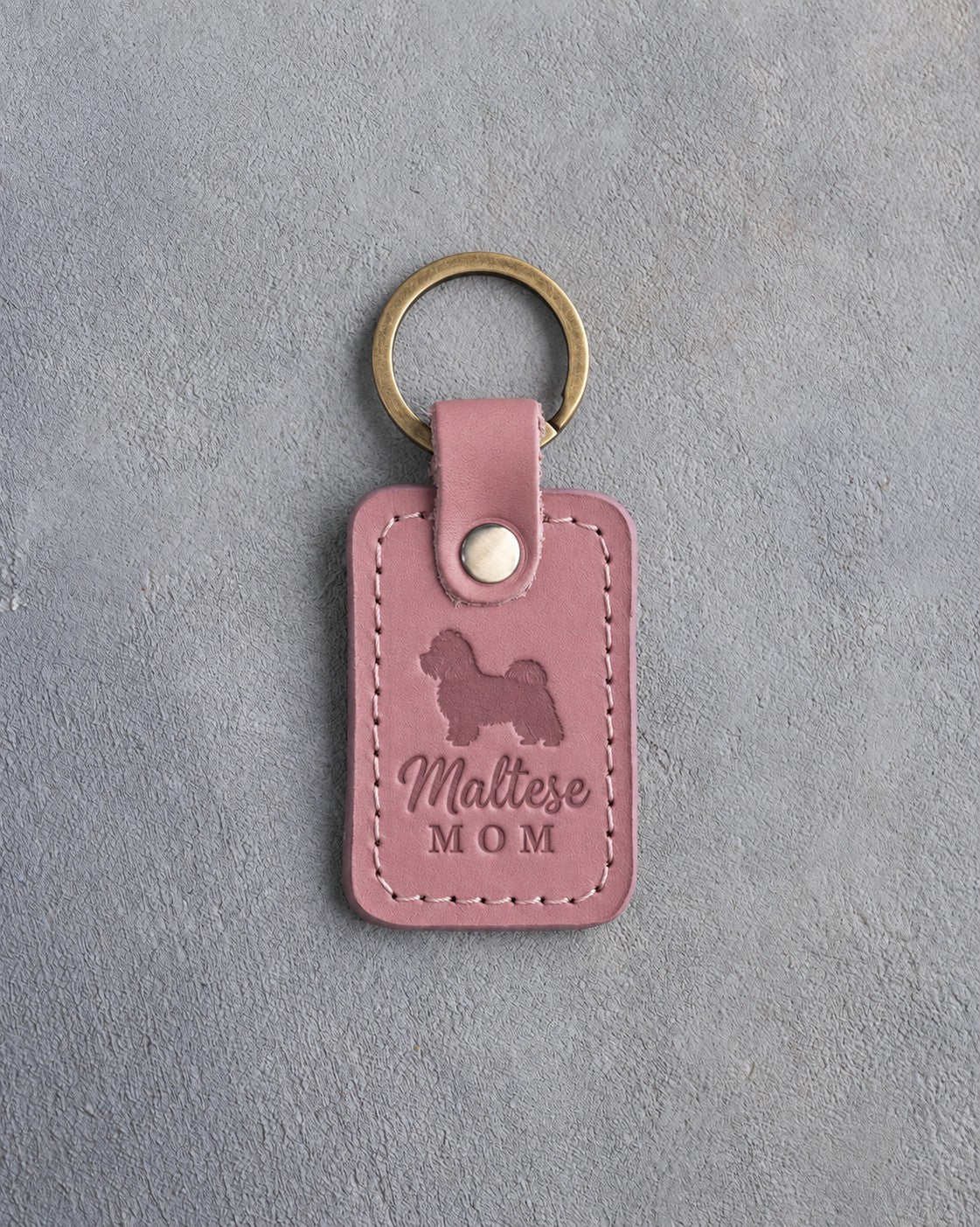 Parisian Blossom pink leather keychain debossed with a Maltese silhouette and the words Maltese MOM, on gray concrete