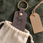Country gray Bella the Maltese keychain held in a warm everyday setting