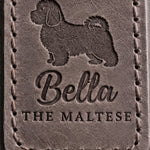Close-up of Bella in brush script and THE MALTESE pressed into country gray full-grain leather beneath a Maltese silhouette