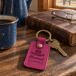 Fuchsia Married A COWBOY keychain on a dark oak ranch kitchen table beside a speckled enamel coffee pot and a chipped mug