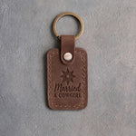 Sicilian brown leather keychain debossed with a spur rowel above Married and A COWGIRL, on gray plaster