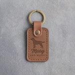 Caramel leather keychain debossed with a Labrador silhouette and the words Merry AND MUDDY, on gray concrete