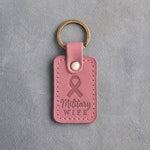 Rosy pink leather keychain debossed with a looped ribbon above the words Military WIFE, on gray concrete