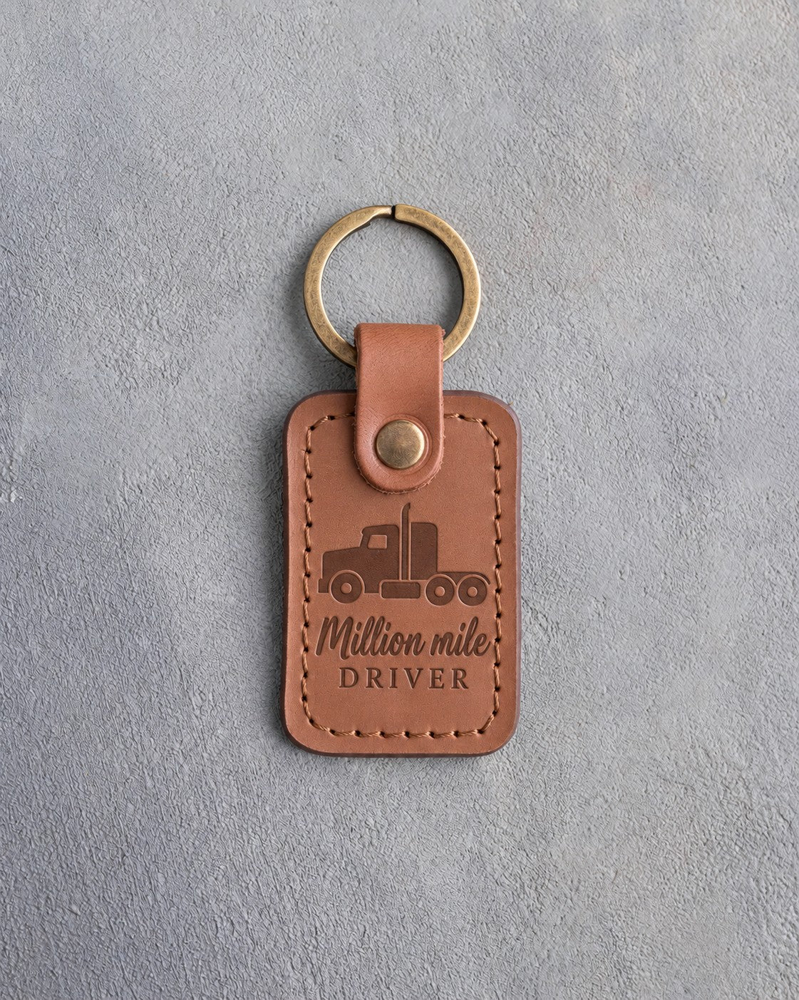 Caramel leather keychain debossed with a semi truck tractor above Million mile and DRIVER