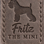 Close-up of Fritz in brush script and THE MINI pressed into country gray full-grain leather beneath a Miniature Schnauzer silhouette