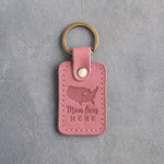 Parisian Blossom pink leather keychain debossed with a map of the lower forty-eight states and a heart at Des Moines above Mom lives and HERE, on gray concrete